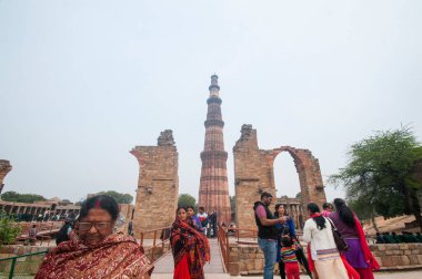 DELHI, Hindistan - 23 Şubat 2018: Kutub Minar 'ı ziyaret eden kimliği belirsiz kişiler, Hindistan' ın en uzun minaresi bir mermer ve kırmızı kumtaşı kulesidir. 