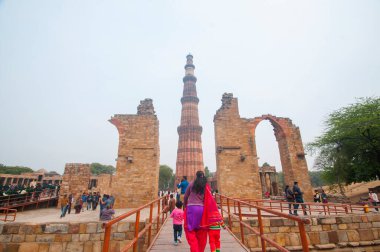 DELHI, Hindistan - 23 Şubat 2018: Kutub Minar 'ı ziyaret eden kimliği belirsiz kişiler, Hindistan' ın en uzun minaresi bir mermer ve kırmızı kumtaşı kulesidir. 
