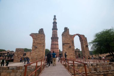 DELHI, Hindistan - 23 Şubat 2018: Kutub Minar 'ı ziyaret eden kimliği belirsiz kişiler, Hindistan' ın en uzun minaresi bir mermer ve kırmızı kumtaşı kulesidir. 