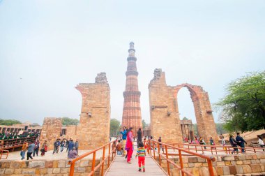 DELHI, Hindistan - 23 Şubat 2018: Kutub Minar 'ı ziyaret eden kimliği belirsiz kişiler, Hindistan' ın en uzun minaresi bir mermer ve kırmızı kumtaşı kulesidir. 