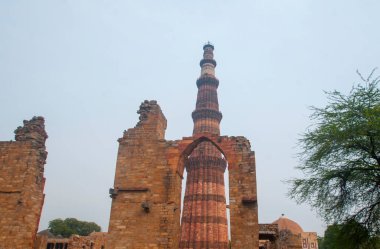 DELHI, Hindistan - 23 Şubat 2018: Kutub Minar 'ı ziyaret eden kimliği belirsiz kişiler, Hindistan' ın en uzun minaresi bir mermer ve kırmızı kumtaşı kulesidir.  