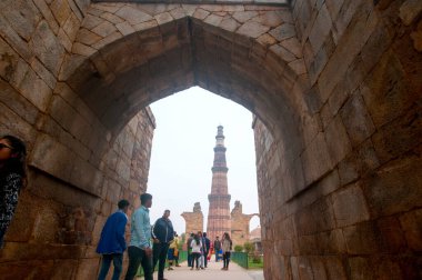 DELHI, Hindistan - 23 Şubat 2018: Kutub Minar 'ı ziyaret eden kimliği belirsiz kişiler, Hindistan' ın en uzun minaresi bir mermer ve kırmızı kumtaşı kulesidir. 