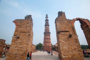 DELHI, Hindistan - 23 Şubat 2018: Kutub Minar 'ı ziyaret eden kimliği belirsiz kişiler, Hindistan' ın en uzun minaresi bir mermer ve kırmızı kumtaşı kulesidir.  