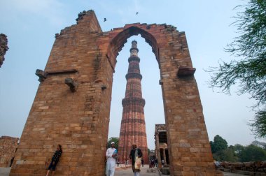 DELHI, Hindistan - 23 Şubat 2018: Kutub Minar 'ı ziyaret eden kimliği belirsiz kişiler, Hindistan' ın en uzun minaresi bir mermer ve kırmızı kumtaşı kulesidir. 