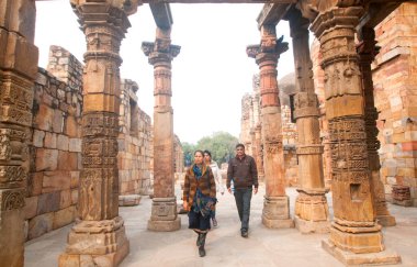 DELHI, Hindistan - 23 Şubat 2018: Kutub Minar 'ı ziyaret eden kimliği belirsiz kişiler, Hindistan' ın en uzun minaresi bir mermer ve kırmızı kumtaşı kulesidir. 
