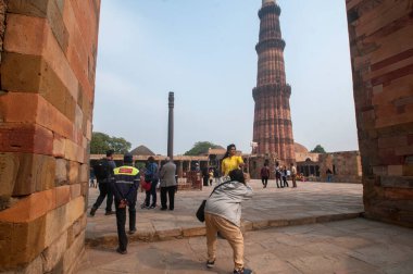 DELHI, Hindistan - 23 Şubat 2018: Kutub Minar 'ı ziyaret eden kimliği belirsiz kişiler, Hindistan' ın en uzun minaresi bir mermer ve kırmızı kumtaşı kulesidir. 