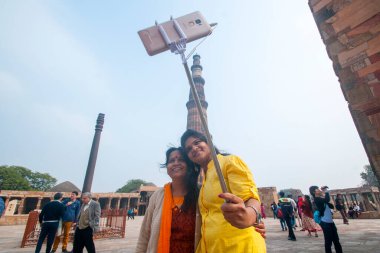 DELHI, Hindistan - 23 Şubat 2018: Kutub Minar 'da özçekim yapan tanımlanamayan turistler, Hindistan' ın en uzun minaresi bir mermer ve kırmızı kumtaşı kulesidir. 