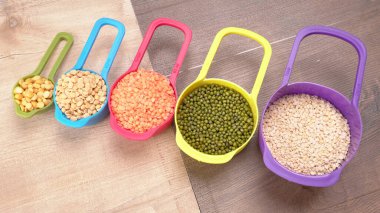 Ahşap arka plandaki renkli kaselerde pişmemiş nabız, tahıl ve tohumlar.