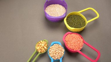 Pişmemiş nabızlar, tanecikler ve tohumlar gri arka planda renkli kaselerde