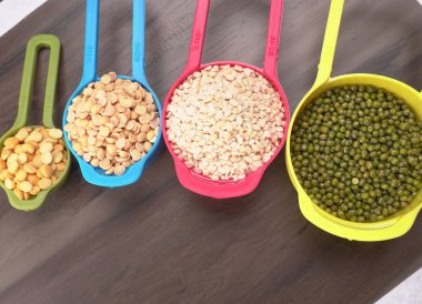 Ahşap arka plandaki renkli kaselerde pişmemiş nabız, tahıl ve tohumlar.