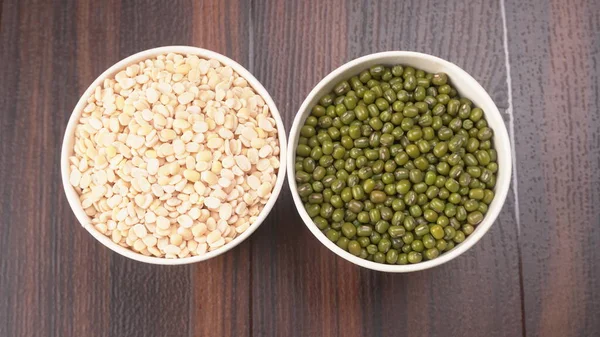 green peas and dried peas in bowls on wooden background