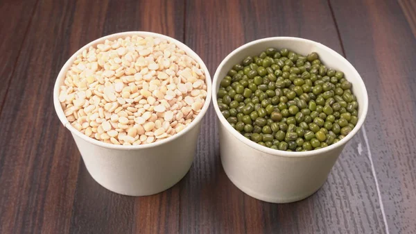 green peas and dried peas in bowls on wooden background
