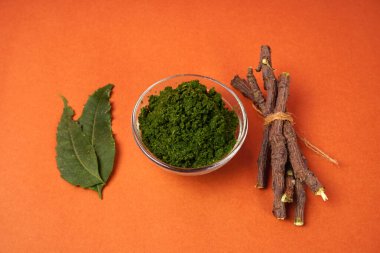 Yaprakları ve turuncu arka planda tahta çubukları olan bir kaseye yapıştır.