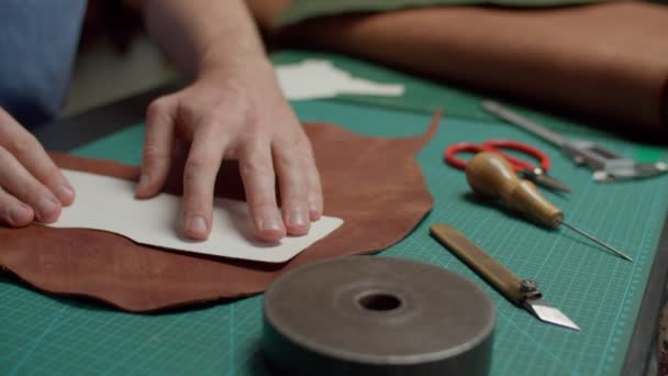 Werkplaatspersoneel dat sjabloon toepast op leren stuk op mat indoor — Stockvideo