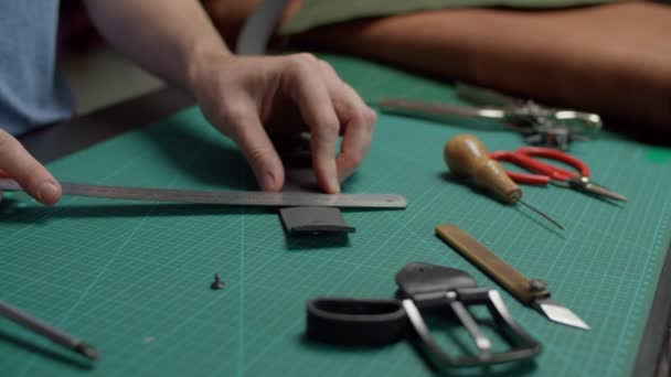 工房内で手作業で革ベルトを短くする職人 — ストック動画