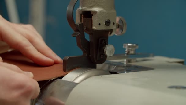 Працівник обробляє край шкіряного шматка, використовуючи ковзання машини в приміщенні — стокове відео