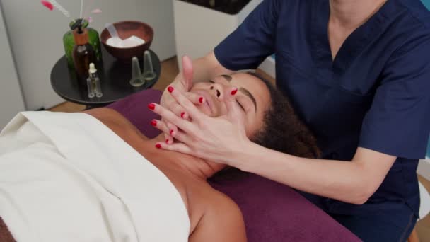 Kompetent specialist massera nedre delarna av kvinnans ansikte inomhus — Stockvideo