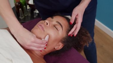 Kozmetik uzmanı evde yüz gerdirme için gua sha kullanıyor.