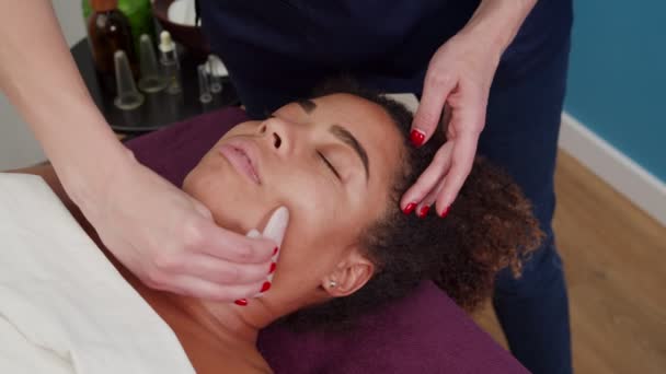 Kosmetikerin benutzt Massage-Tool gua sha für Gesichtsstraffung in Innenräumen — Stockvideo