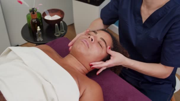 Кваліфікований косметолог застосовує техніку масажу обличчя в приміщенні — стокове відео