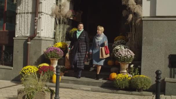 Dojrzałe kobieta para z papierowe torby chodzenie na dół na zewnątrz — Wideo stockowe