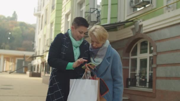 Зрелые женщины просматривают телефон, используя мобильное приложение через интернет на открытом воздухе — стоковое видео