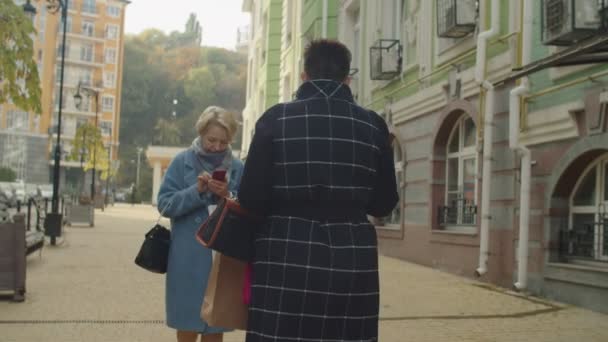 Zwei reife Frauen, besessen von Telefonen, die sich im Freien begegnen — Stockvideo