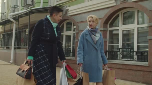 Anciana amiga mostrando compras en paquete de papel a su pareja al aire libre — Vídeos de Stock