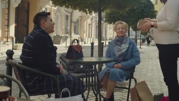 Starší přítelkyně sedí, objednávají servírku venku — Stock video