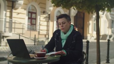 Olgun bir kadın dışarıda akıllı telefon aracılığıyla iş görüşmesi yapıyor.