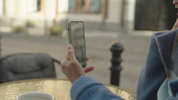 Oudere vrouw met behulp van mobiele telefoon app voor online video bellen buiten — Stockvideo
