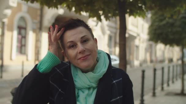 Porträtt av glad medelålders kvinna med kort hår utomhus — Stockvideo