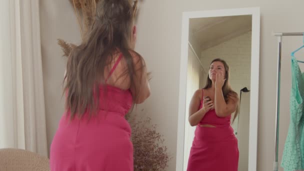 Позитивная пухлая взрослая женщина увлажняет лицо кремом в помещении — стоковое видео
