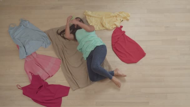 Толстая женщина с помощью смартфона, покупки онлайн лежит на полу в помещении — стоковое видео
