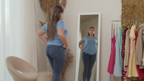 Donna grassoccia allegra in jeans ammirando il riflesso in specchio all'interno — Video Stock