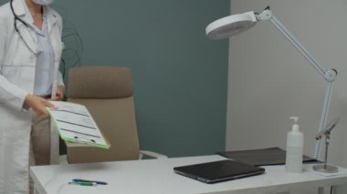 Kadın doktor maskesini çıkarıyor, içeride çalışmaya devam ediyor.