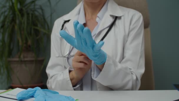 Midsection of female doctor putting medical protective gloves indoors — Stock video