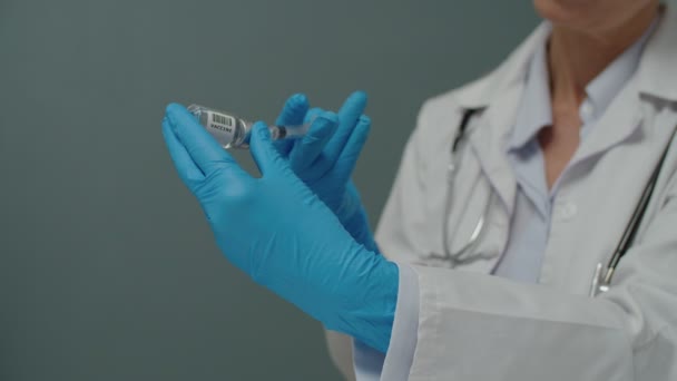 Manos de cerca en guantes médicos que llenan la jeringa con la vacuna en el interior — Vídeos de Stock