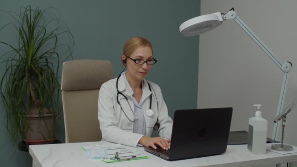 Médico femenino usando laptop, participando en videoconferencia en interiores — Vídeos de Stock