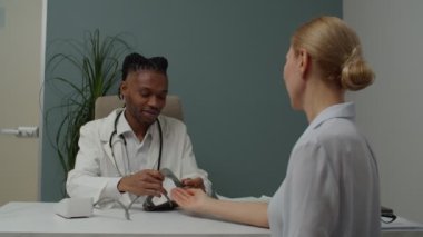 Genç erkek doktor içeride kadın hastaya kan basıncını ölçüyor.