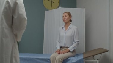 Doktor içeride olgun bir kadına test sonuçlarını açıklamak için tablet kullanıyor.