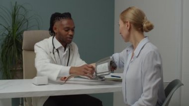 Erkek doktor içeride kan basıncını ölçerek hastayı muayene ediyor.