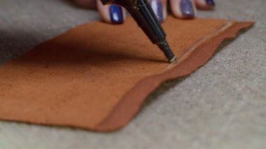 Kapalı kapılar ardında deri parçasına yapıştırıcı süren işçi elleri.