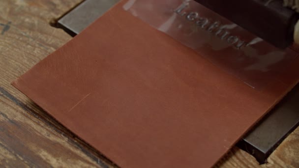 Skilled workman using heat embossing equipment to leather piece indoor — Stock Video