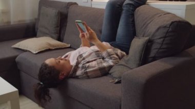 İnternetteki kadın mesajlaşması, evdeki koltukta internet üzerinden mobil uygulama kullanımı.