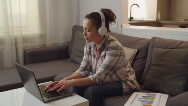 Frau benutzt Laptop, hört Musik, jemand ruft sie nach draußen — Stockvideo