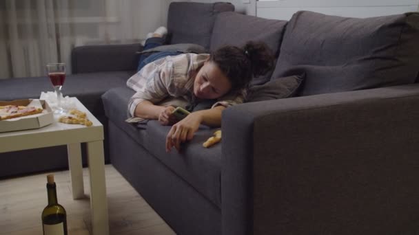 Депресивна доросла жінка лежить на дивані, що зменшує мобільний дзвінок у приміщенні — стокове відео