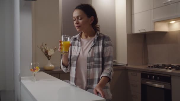 Радісна доросла жінка п'є сік, насолоджується смаком, посміхається в приміщенні — стокове відео