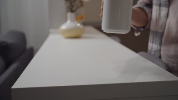 Tangan wanita menaruh gelas putih dengan minuman di meja dapur di dalam ruangan — Stok Video