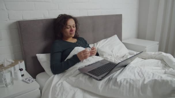 Sick adult woman lying in bed, watching video, movie on laptop indoors — 图库视频影像